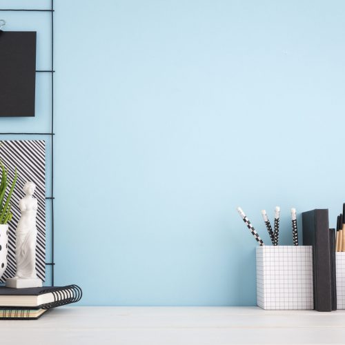 Home office creative desk with supplies, and blue wall. - Obraz